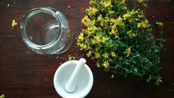 Glas und Mörser neben frischen gelben Blumen auf Holz.