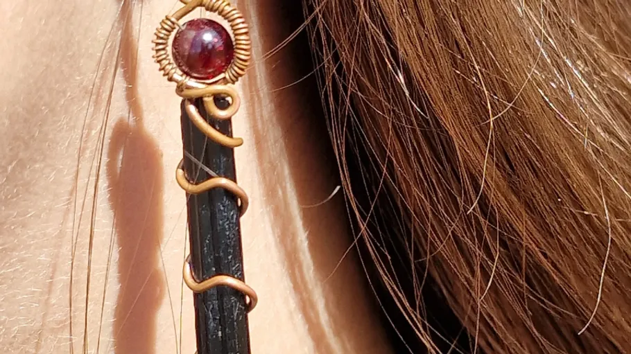 Earring with black stone hangs next to brown hair.