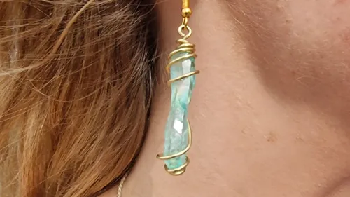 Earrings with polished turquoise stone hang on the ear.