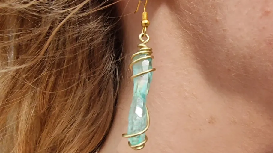 Earrings with polished turquoise stone hang on the ear.