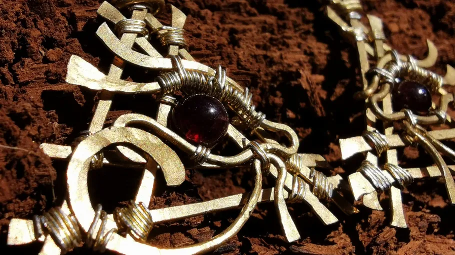The piece of jewellery shines with red stone on a wooden background.