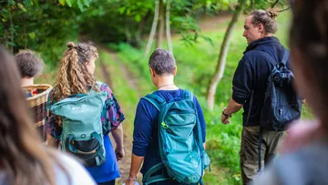 Gruppe geht auf einem schmalen Weg durch den Wald.
