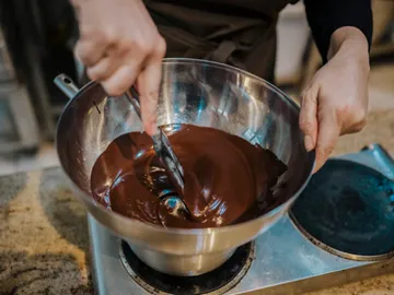 Bowl of melted chocolate is stirred in the kitchen.