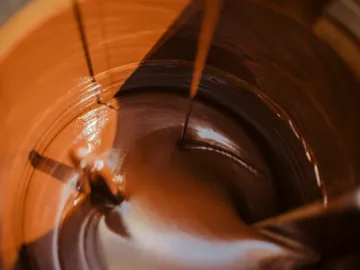 Chocolate runs in a bowl, shiny and creamy.