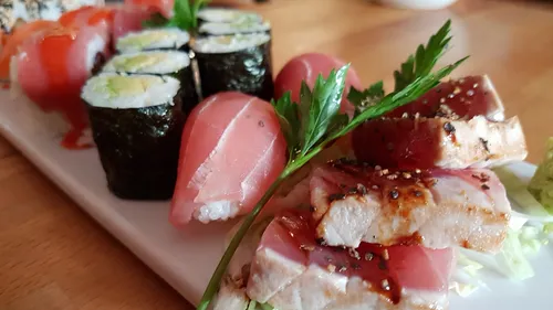 Sushi-Platte mit verschiedenen Sushi-Arten auf weißem Teller.