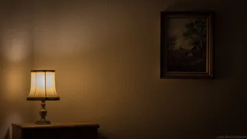 A lamp emits warm light in a dark room.