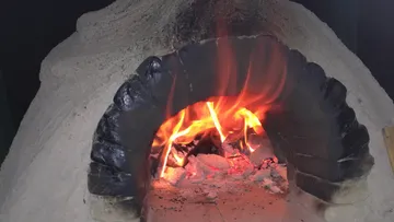 A fire burns in a stove made of large stones.