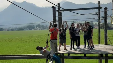 People use a zip line on an outdoor platform.