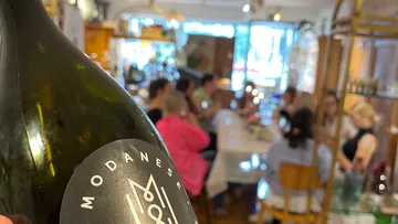 A wine bottle is held while guests eat and talk.