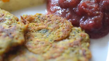 Kichererbsenpfannkuchen liegen auf einem weißen Teller neben Chutney.