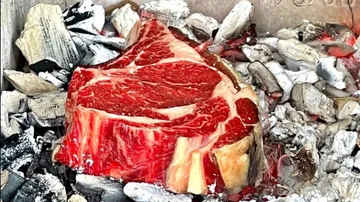 Ein Steak brät im Glutbett eines Grills.