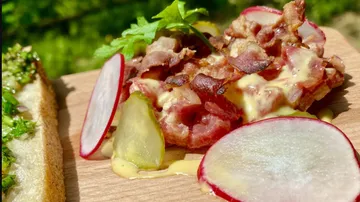 Speise mit Speck, Senf und Radieschen auf Holzbrett.