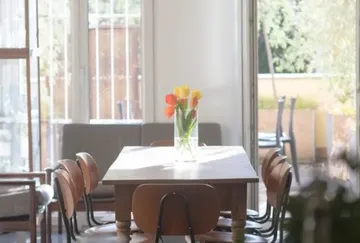 A table with tulips is placed in a bright room.
