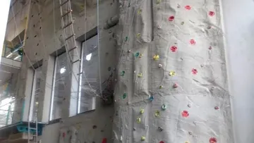 Climbing wall with colorful handles in a modern building.