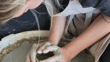 A person forms clay on a potter's wheel.