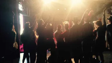 Group of people raise their hands in front of a stage.