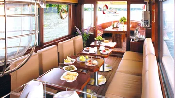 Elegantes Boot, gedeckte Tische mit Speisen, am Wasser.