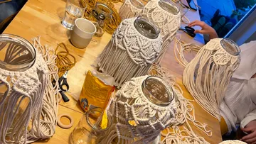 Glass jars are wrapped in macrame, in a creative setting.