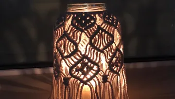 Candle in a decorative holder glows weakly in the dark.