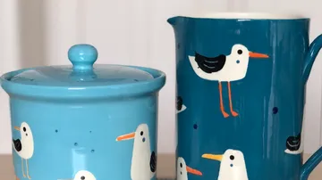 Blaue Keramiktöpfe mit Möwenmotiven stehen auf einem Tisch.