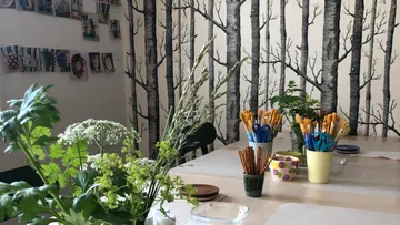 Table with tools and plants in front of tree wallpaper.