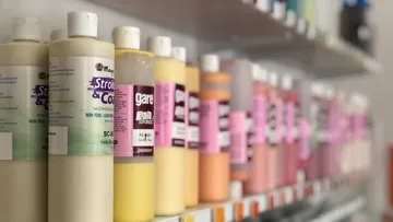 Farbenflaschen stehen in einem Regal, verschiedene Farben sichtbar.