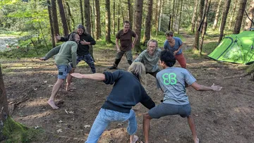 Gruppe von Personen tanzt aktiv im Wald.