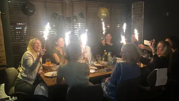 Celebrating women hold spr sparklers at a table.