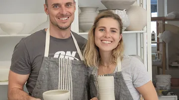 Paar mit Töpferwaren lächelt in einem Atelier.