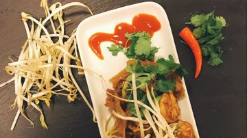 Fried noodles with shrimp, coriander and chilli on plate.