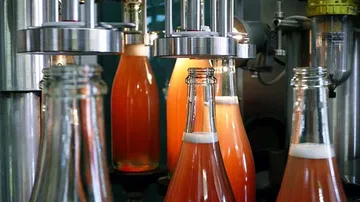Bottles are filled with beverage in a bottling plant.