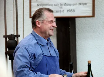 A man smiles while working on a bottle at the winery.