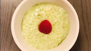 Grüne Dessertcreme mit Himbeere in einer weißen Schüssel.