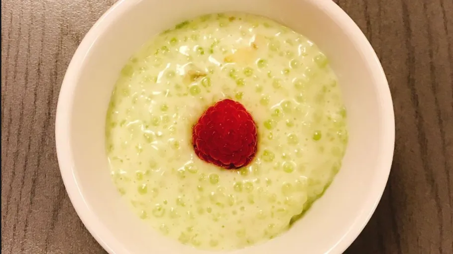 Green dessert cream with raspberries in a white bowl.