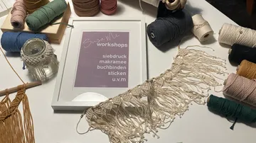 Garnrollen liegen verstreut, Kunstwerkstätte wird vorbereitet.