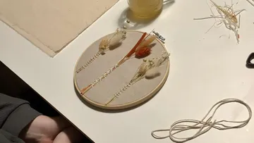 Hoop with dried flowers surrounded by craft materials.