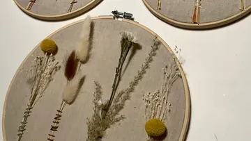 Embroidered frames with dried flowers hang on the wall.