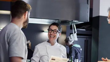 Koch smiles and talks to diners in the restaurant.