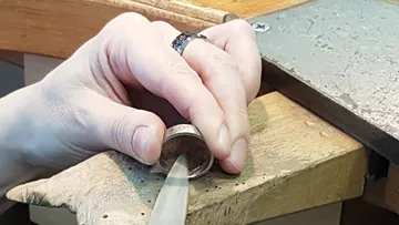 Eine Hand arbeitet mit einer Feile an einem Ring.
