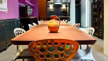 Langer Tisch mit buntem Krug in modernem Essbereich.