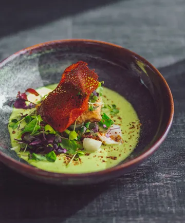 Eine Schüssel mit cremiger Suppe und Gemüse garnieren.