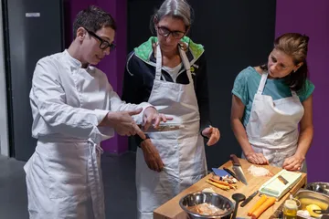 Chefs cut vegetables and study together in a kitchen.