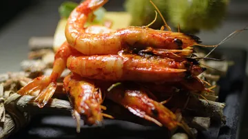 Prawns are served on a wooden board.