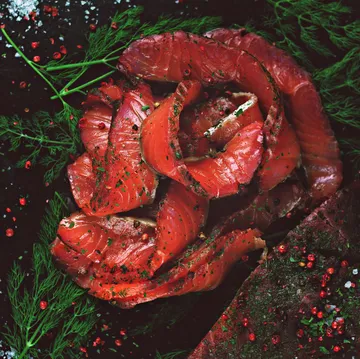 Smoked salmon in a rose-like arrangement, surrounded by herbs.
