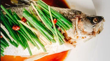 Kochfisch mit Frühlingszwiebeln und Chili in Soße.