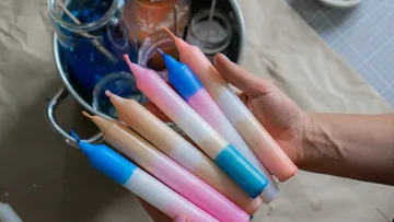 Hand holding colorful dip-dyed candles.