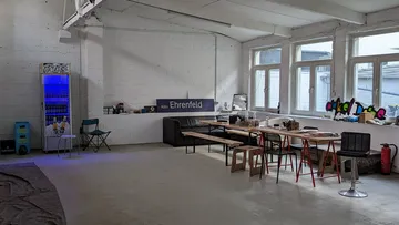 Eingangshalle mit Tischen, Stühlen und einem Kühlschrank.