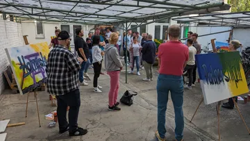 Group of people discussing works of art in a courtyard.