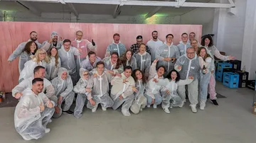 Group of people in white suits pose happily.