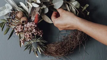 Händewring an einem dekorativen Kranz aus Trockenblumen.